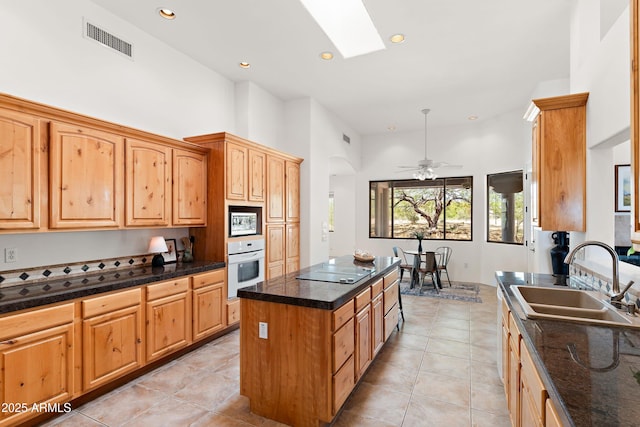 kitchen with built in microwave, visible vents, a sink, a center island, and white oven