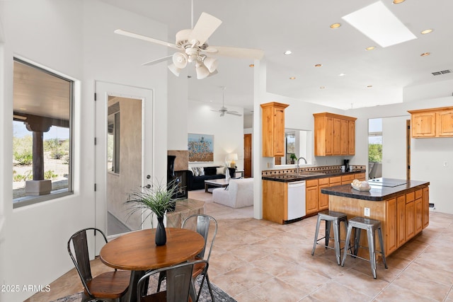 kitchen with dark countertops, a center island, a ceiling fan, white dishwasher, and recessed lighting