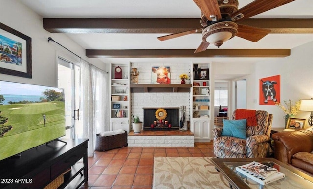 living room featuring ceiling fan, a stone fireplace, tile patterned flooring, and beam ceiling