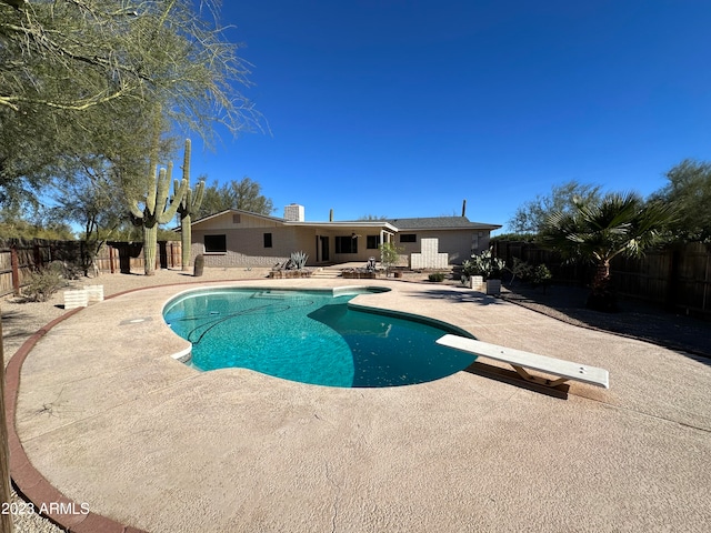 view of swimming pool featuring a patio and a diving board