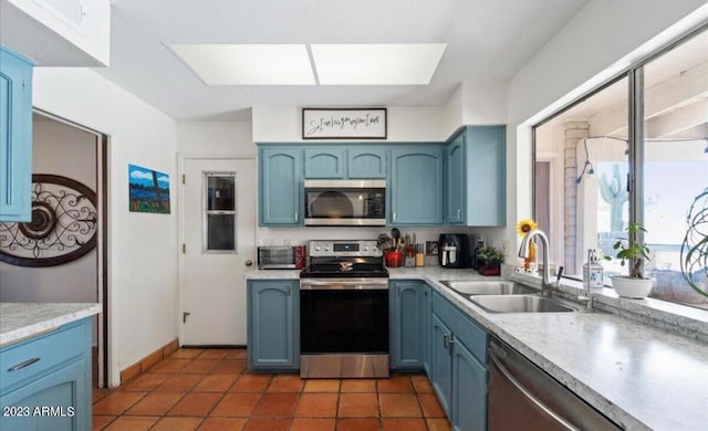 kitchen featuring dark tile patterned flooring, sink, blue cabinetry, and stainless steel appliances