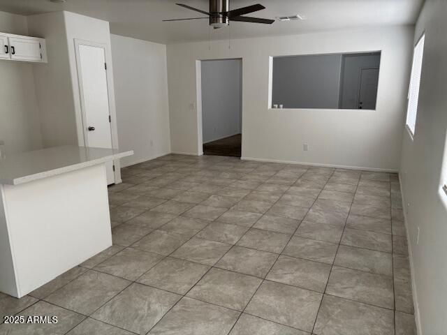 spare room with baseboards, visible vents, and a ceiling fan