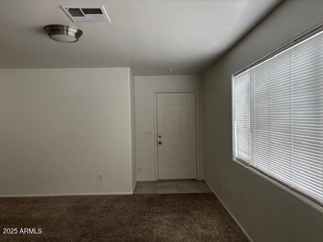 empty room featuring baseboards, visible vents, and light colored carpet