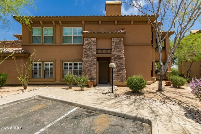 19700 N 76th St Unit 1040, Scottsdale, AZ 85255 - view of front facade with stucco siding, a tiled roof, uncovered parking, a patio area, and a chimney