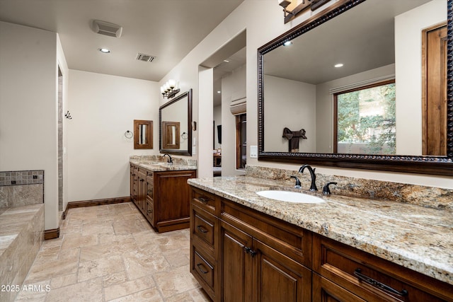 4610 E Meadowview Dr, Gilbert, AZ 85298 - full bathroom with two vanities, baseboards, stone tile flooring, recessed lighting, and a bath