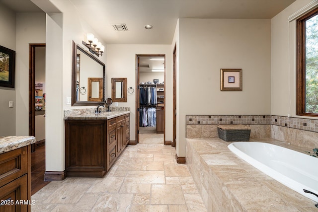 4610 E Meadowview Dr, Gilbert, AZ 85298 - full bath featuring vanity, stone tile floors, a bath, a spacious closet, and recessed lighting