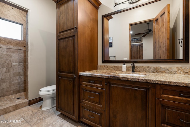 4610 E Meadowview Dr, Gilbert, AZ 85298 - bathroom with vanity, toilet, a tile shower, ceiling fan, and stone tile flooring