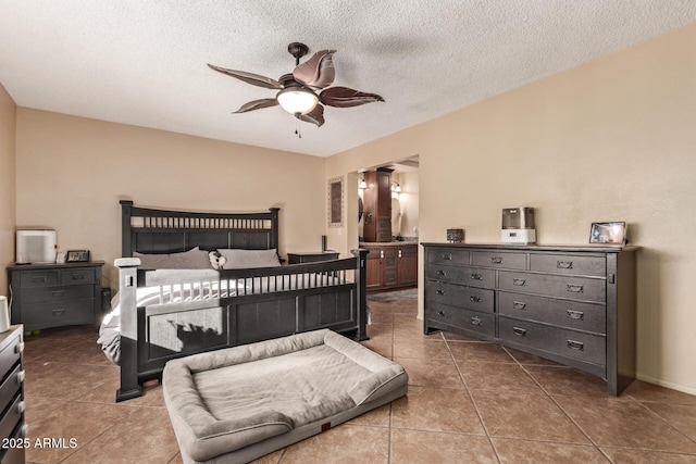 tiled bedroom featuring a textured ceiling, ensuite bathroom, and ceiling fan