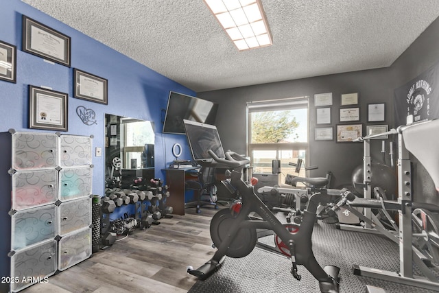 exercise area with hardwood / wood-style floors and a textured ceiling