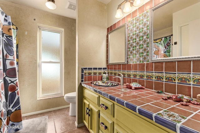 bathroom featuring tile patterned flooring, vanity, toilet, and a healthy amount of sunlight