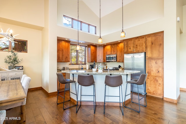 kitchen featuring pendant lighting, dark wood-type flooring, light stone countertops, and appliances with stainless steel finishes