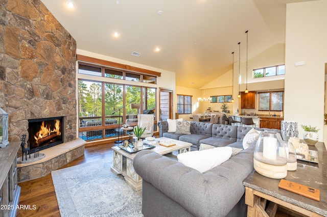 living room with a stone fireplace, dark hardwood / wood-style floors, high vaulted ceiling, and plenty of natural light