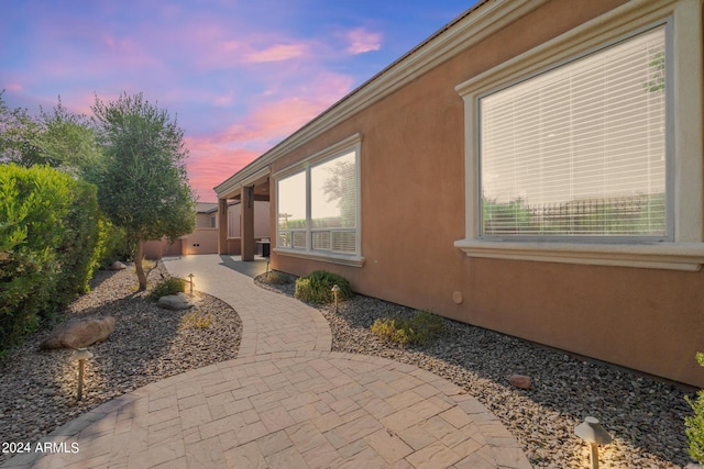 property exterior at dusk featuring a patio area