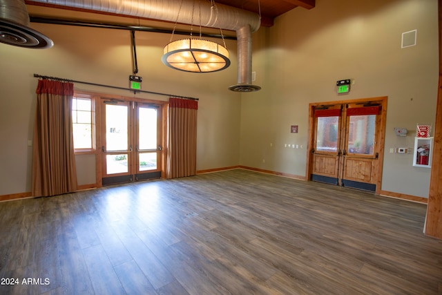 interior space with a towering ceiling, wood-type flooring, and french doors