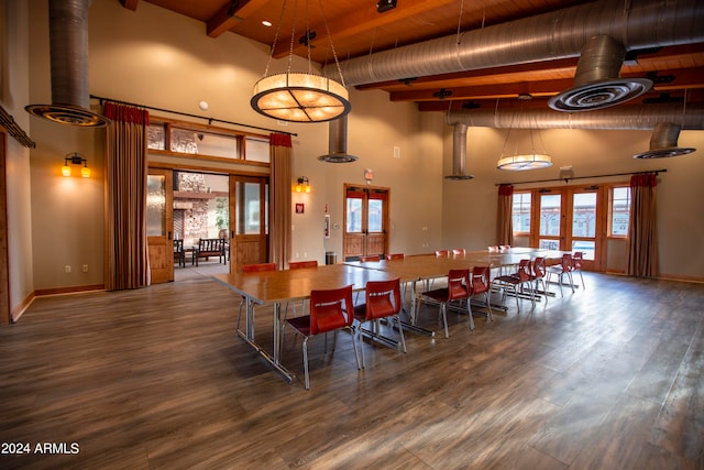 dining space with hardwood / wood-style floors, a towering ceiling, and french doors