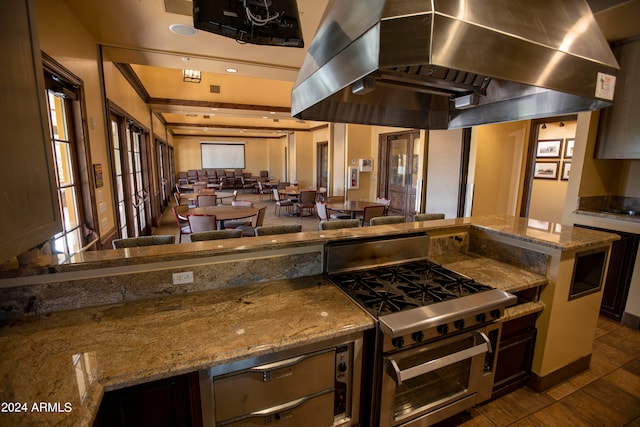 kitchen with double oven range, extractor fan, dark tile patterned floors, and stone counters