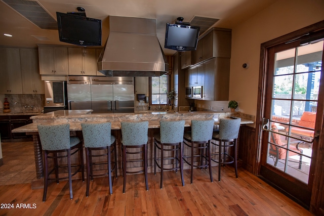 kitchen featuring a kitchen bar, light stone countertops, light hardwood / wood-style floors, stainless steel appliances, and kitchen peninsula