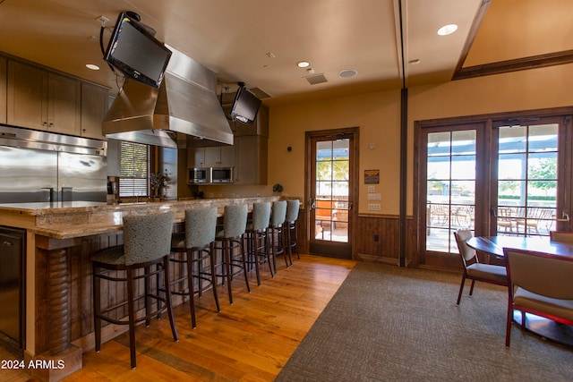 kitchen featuring light hardwood / wood-style floors, stone counters, french doors, fridge, and kitchen peninsula