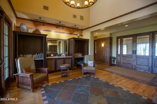 foyer entrance with rail lighting, a chandelier, and wood-type flooring