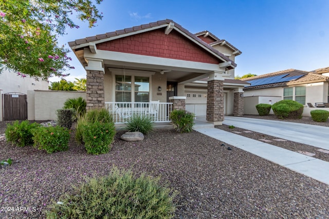 craftsman house featuring solar panels, covered porch, and a garage