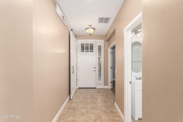 hallway featuring sink, light tile patterned floors, and a barn door