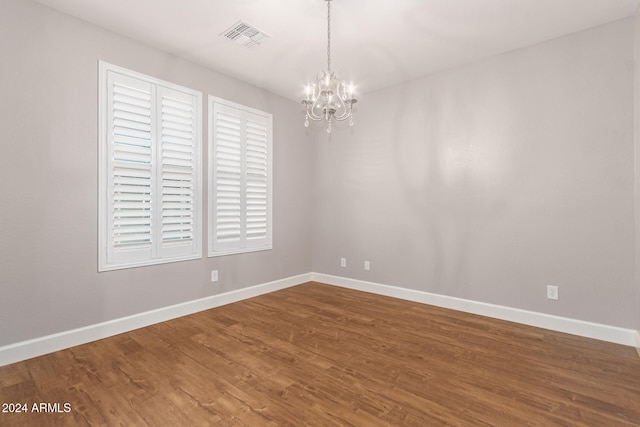 spare room featuring hardwood / wood-style flooring and a notable chandelier