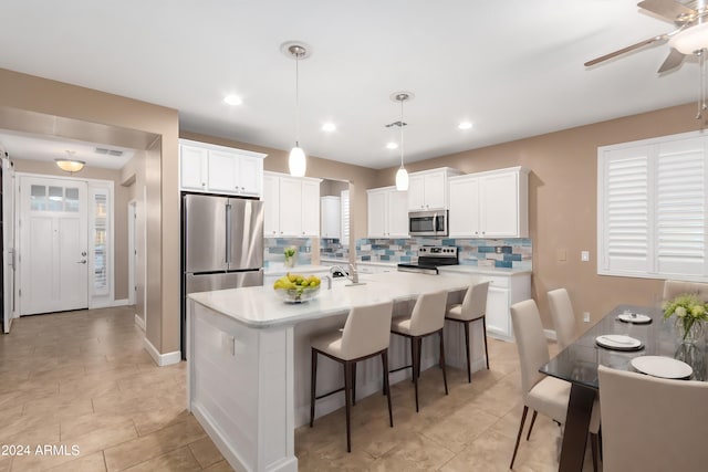 kitchen with backsplash, stainless steel appliances, white cabinetry, pendant lighting, and ceiling fan