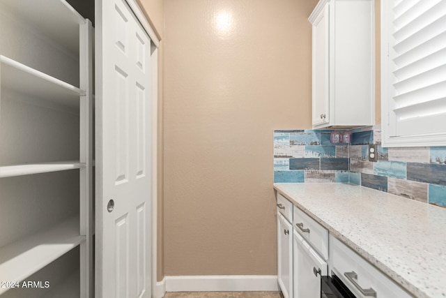 kitchen with light stone counters, white cabinetry, and tasteful backsplash