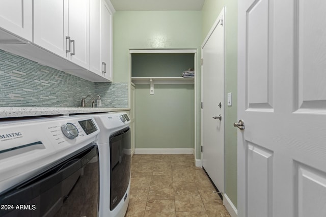 laundry room with light tile patterned floors, washing machine and clothes dryer, and cabinets