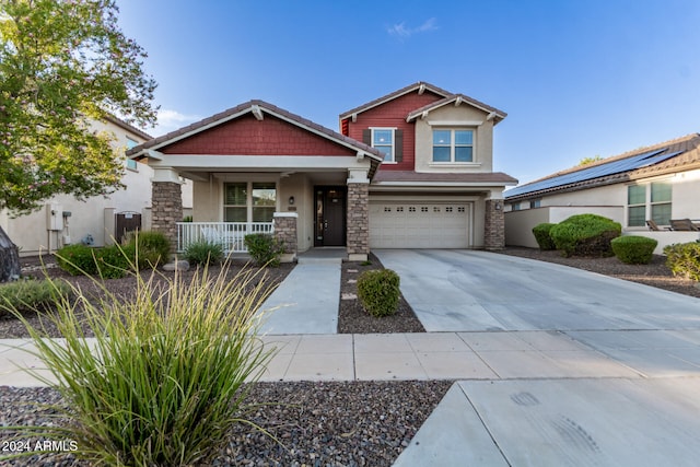 craftsman inspired home with a porch, solar panels, and a garage