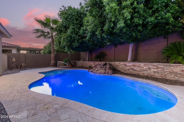 pool at dusk featuring a patio area