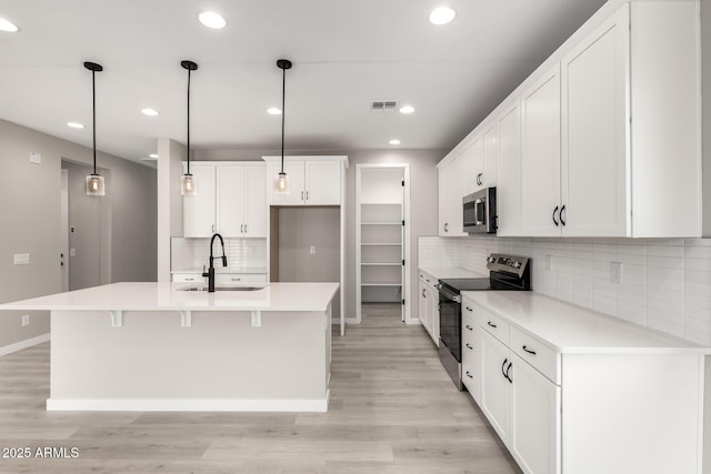 kitchen featuring visible vents, light wood-type flooring, appliances with stainless steel finishes, white cabinetry, and a sink