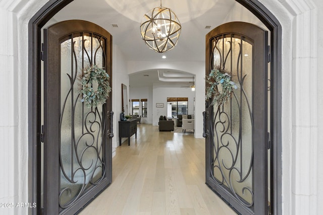 foyer entrance featuring ceiling fan with notable chandelier and light wood-type flooring