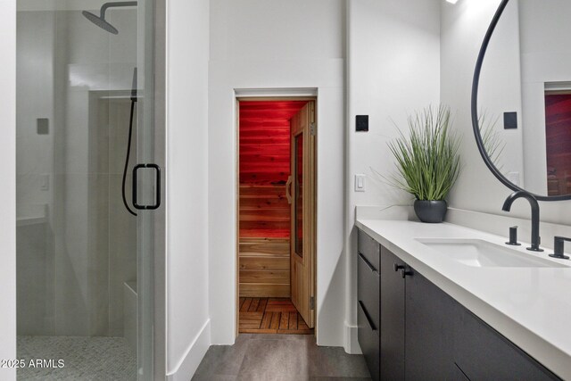 bathroom with a shower with door, vanity, and parquet floors