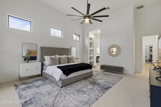 bedroom featuring ceiling fan, carpet flooring, multiple windows, and a high ceiling