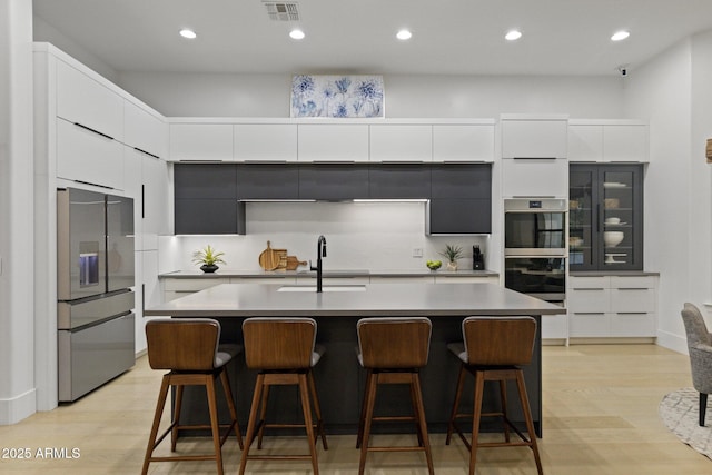 kitchen with an island with sink, appliances with stainless steel finishes, sink, and a breakfast bar area