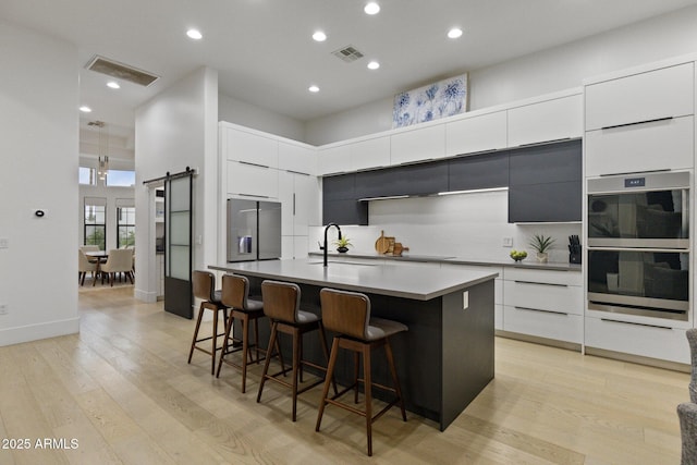 kitchen with a kitchen breakfast bar, stainless steel appliances, a high ceiling, an island with sink, and a barn door