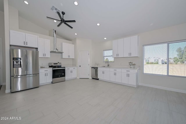 kitchen featuring white cabinetry, wall chimney range hood, stainless steel appliances, and vaulted ceiling