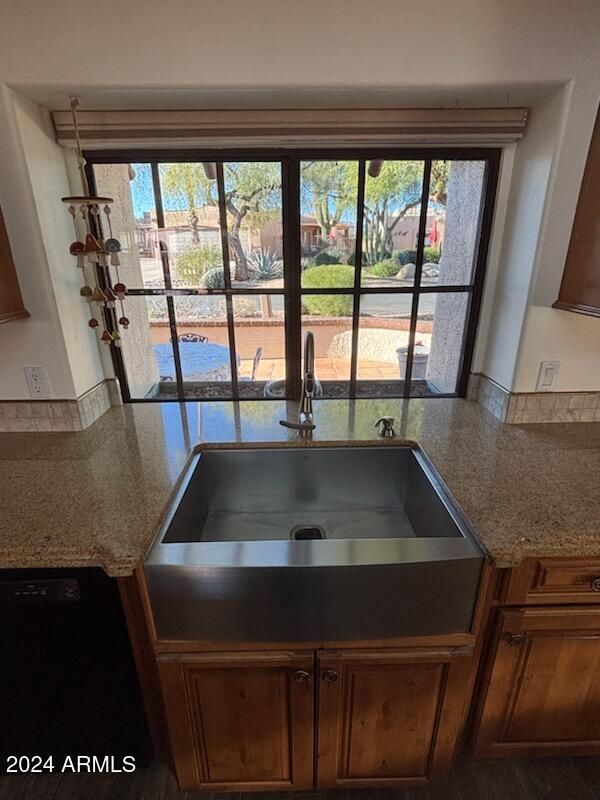 kitchen with light stone countertops, dishwasher, and sink