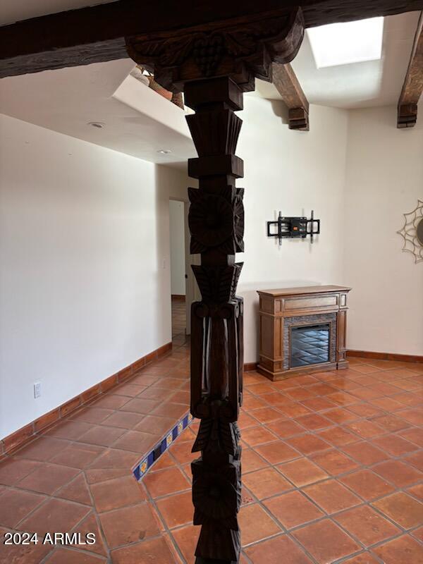 unfurnished living room with a fireplace, tile patterned floors, and beamed ceiling