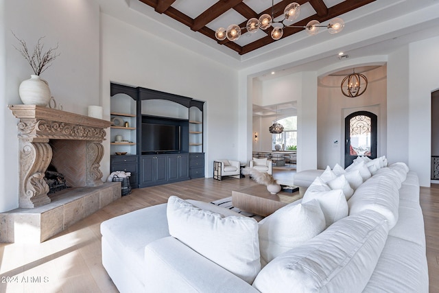 living room featuring coffered ceiling, light hardwood / wood-style flooring, beamed ceiling, a notable chandelier, and a towering ceiling