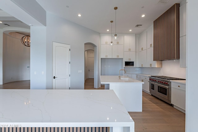 kitchen featuring a center island with sink, pendant lighting, white cabinets, and stainless steel appliances