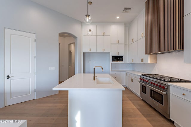 11328 E Dreyfus Ave, Scottsdale, AZ 85259 - kitchen featuring double oven range, black microwave, wall chimney exhaust hood, arched walkways, and light wood-style floors
