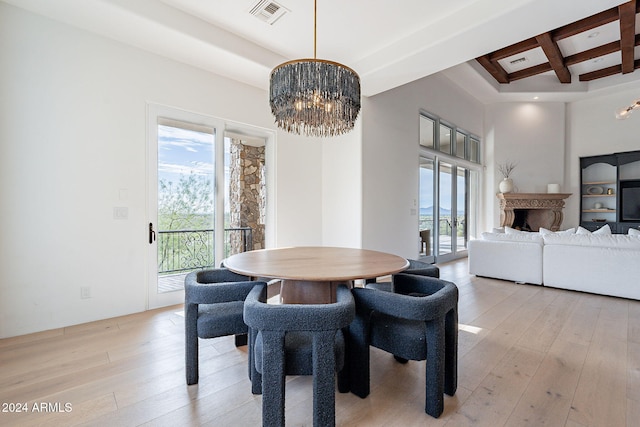 dining area with beam ceiling, an inviting chandelier, and light hardwood / wood-style flooring