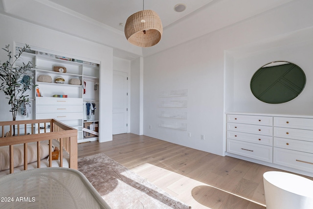 bedroom with light hardwood / wood-style floors, a crib, and a closet