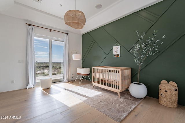 bedroom featuring a nursery area and wood-type flooring