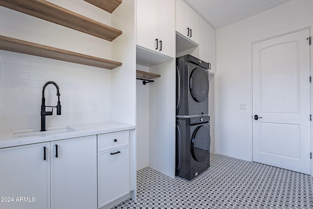 clothes washing area with sink, cabinets, and stacked washer / dryer