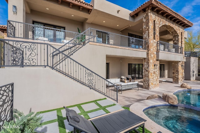 rear view of property with an outdoor living space, a patio, and a pool with hot tub