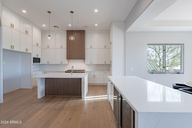 11328 E Dreyfus Ave, Scottsdale, AZ 85259 - kitchen featuring a center island with sink, light wood-style floors, stainless steel microwave, recessed lighting, and white cabinetry