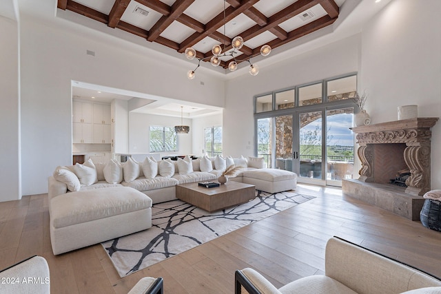 living room featuring beamed ceiling, a towering ceiling, light hardwood / wood-style floors, and coffered ceiling